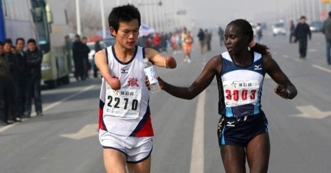 Kenijska zawodniczka podaje wodę swojemu chińskiemu konkurentowi