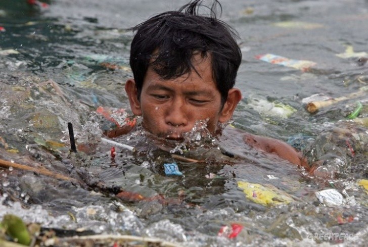 Mężczyzna płynący przez śmieci w zatoce Manila.