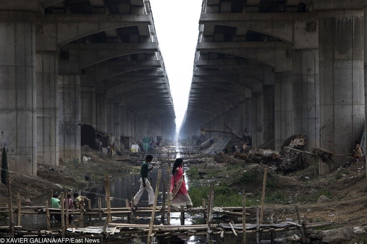 Ludzie przechodzący przez prowizoryczny most nad kanałem w Danapur. Obok niego bawią się też dzieci.
