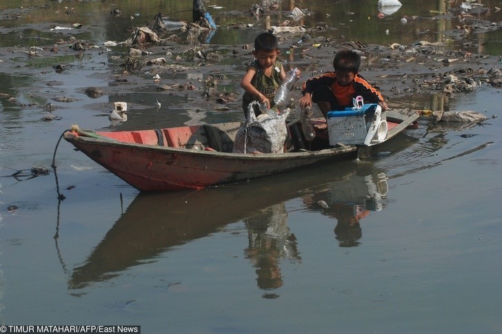Indonezyjscy chłopcy wyciągający rzeczy z zanieczyszczonej rzeki.