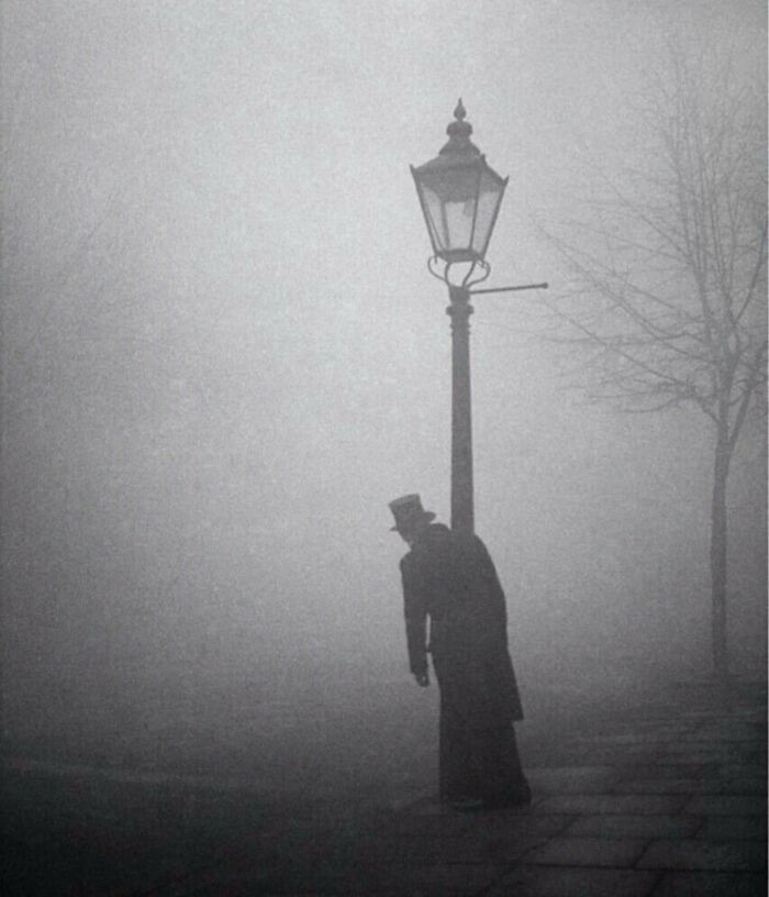 16. Pijany mężczyzna w cylindrze i fraku trzymający się lampy, Londyn, 1934