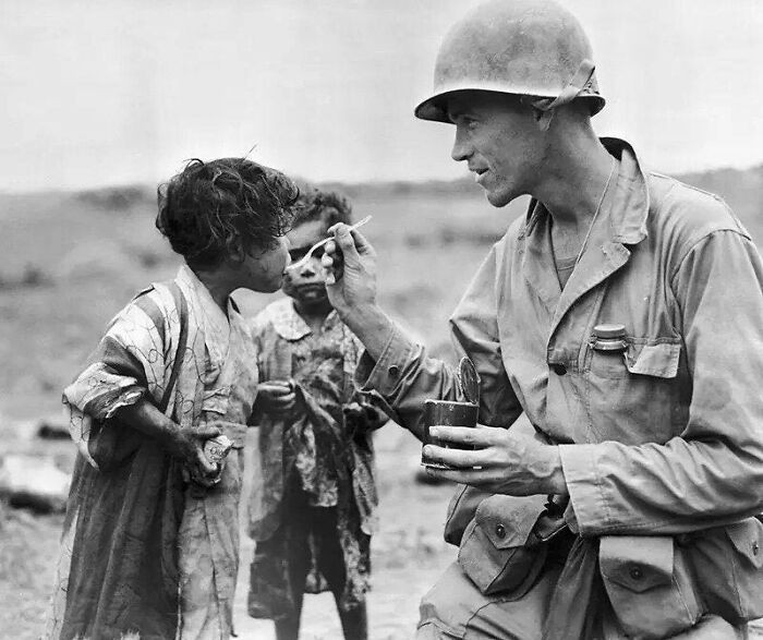 "Amerykański żołnierz dzieli się swoimi racjami żywnościowymi z dwoma japońskimi dziećmi, Okinawa, 1945