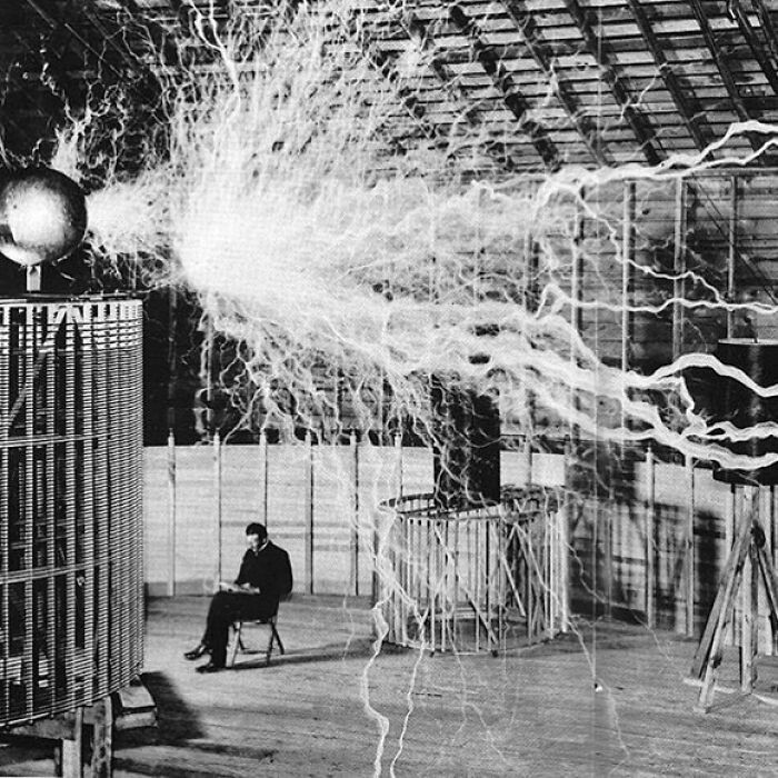 Nikola Tesla siedzący w swoim laboratorium przy jego "przekaźniku powiększającym", 1899