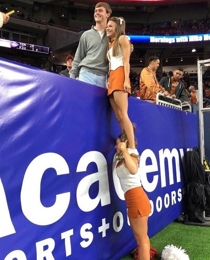 1. "Cheerleaderka pomaga koleżance zrobić sobie zdjęcie z fanem."