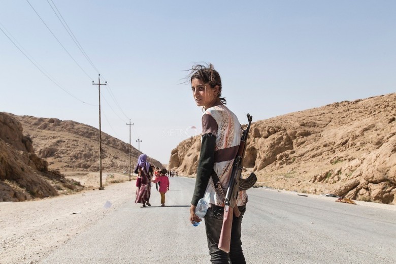 Młoda dziewczyna niosąca karabin aby chronić swoją rodzinę przed ISIS.