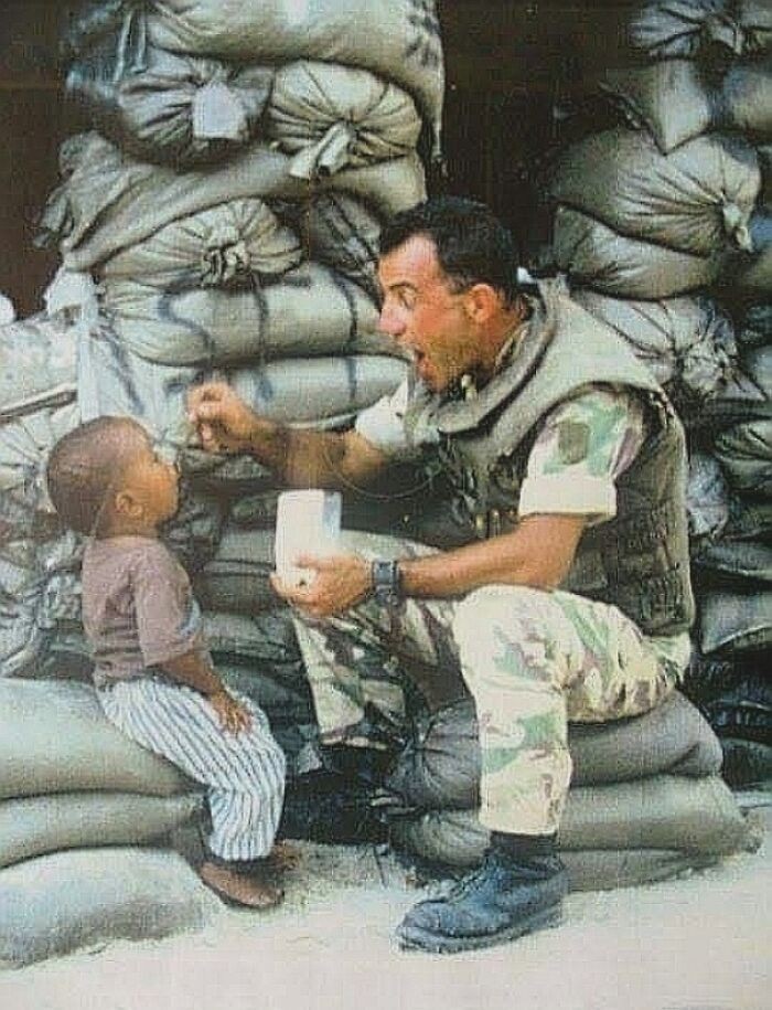 Włoski żołnierz karmiący lokalną sierotę. Mogadiszu, 1993