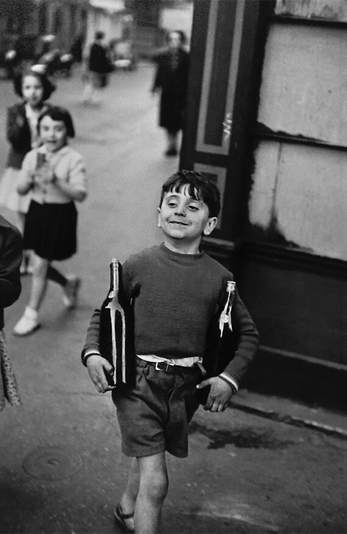 "Zadowolony młody chłopiec niosący dwie butelki wina. Paryż, rok 1954"