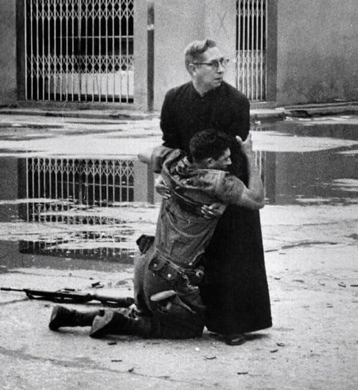 9. Ksiądz podtrzymuje umierającego żołnierza, podczas gdy wokół nich świszczą naboje, Wenezuela, 1962