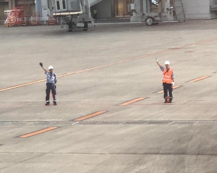 Pracownicy lotniska kłaniają się i machają pasażerom opuszczającym samoloty.