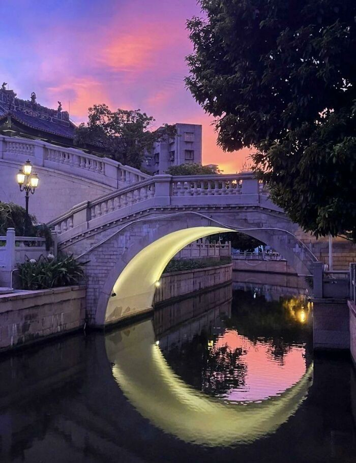 Światło pod tym mostem odbija się w wodzie, tworząc księżyc.