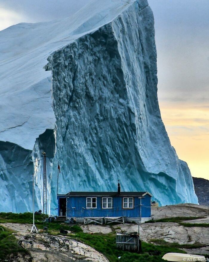 Góra lodowa mijająca dom w Grenlandii