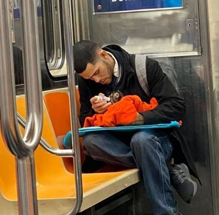 "Facet karmiący małego kotka w metrze"