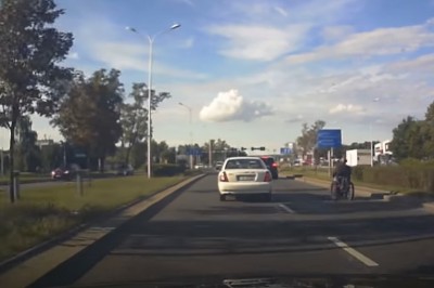 Gość na turbo wózku inwalidzkim jedzie między autami