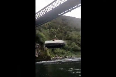 Motorówka wykorzystana jako huśtawka pod mostem na rzece